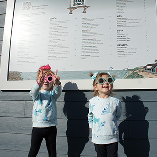 Children wearing sunglasses near the menu wall